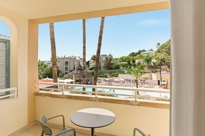 A balcony with a view of a pool, palm trees, and buildings.