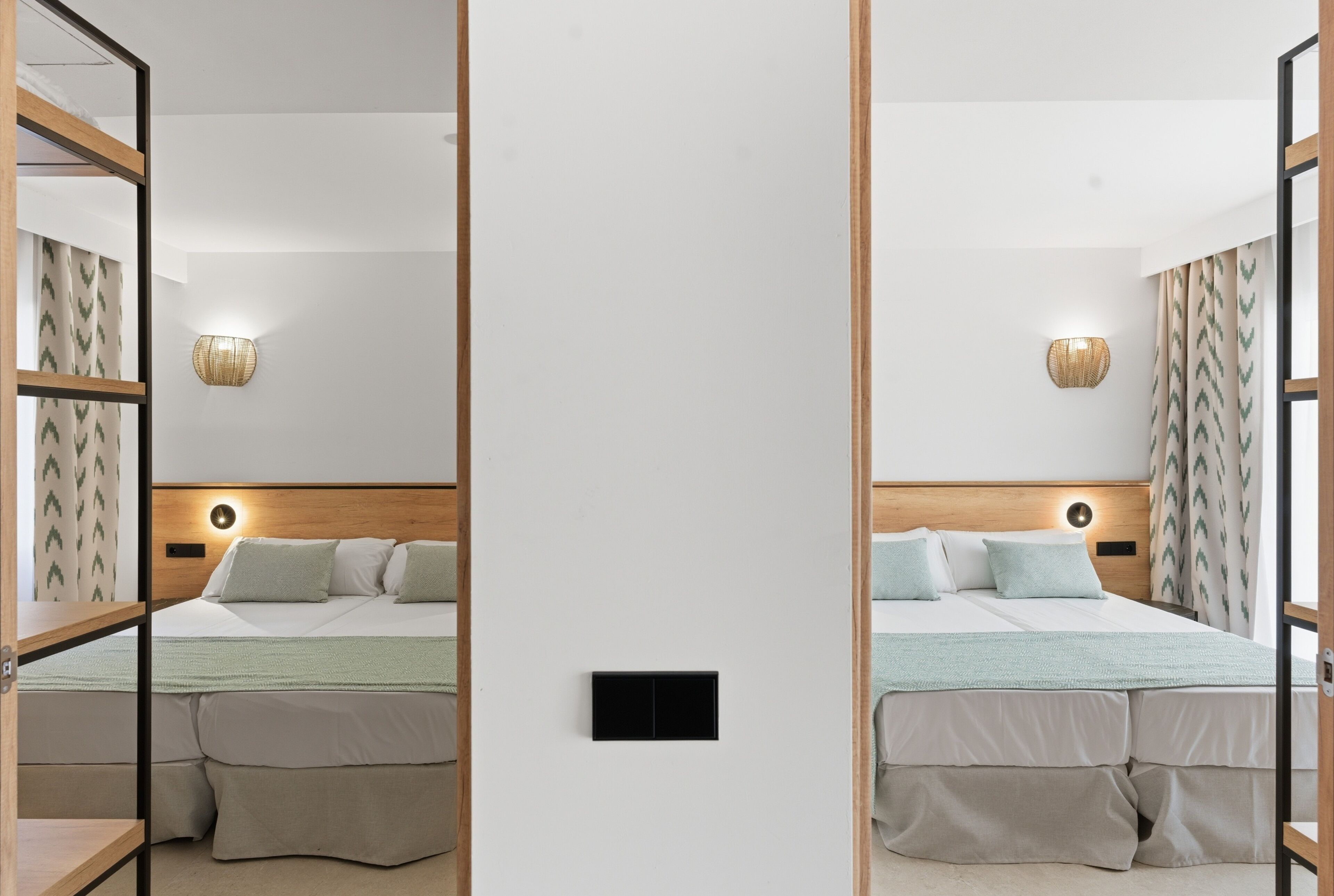 A mirrored room with a bed, bedside lamps, and a wall-mounted light fixture.