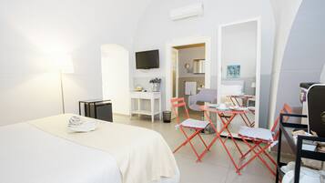 Una camera d'albergo con un letto, una scrivania, una sedia, una televisione e un angolo cottura.