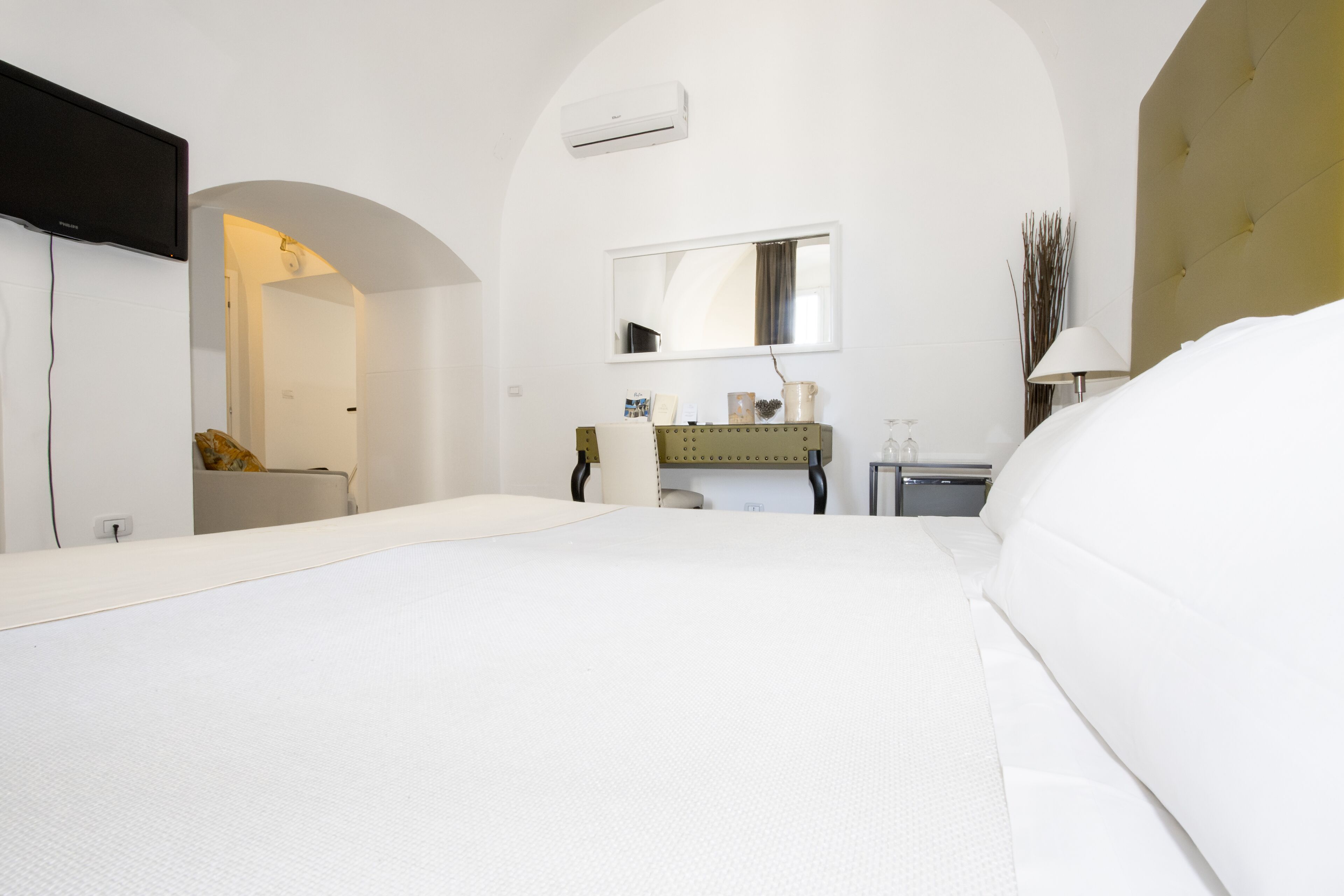 A hotel room with a large bed, a vanity with a mirror, and a small desk.