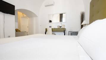 A hotel room with a large bed, a vanity with a mirror, and a small desk.
