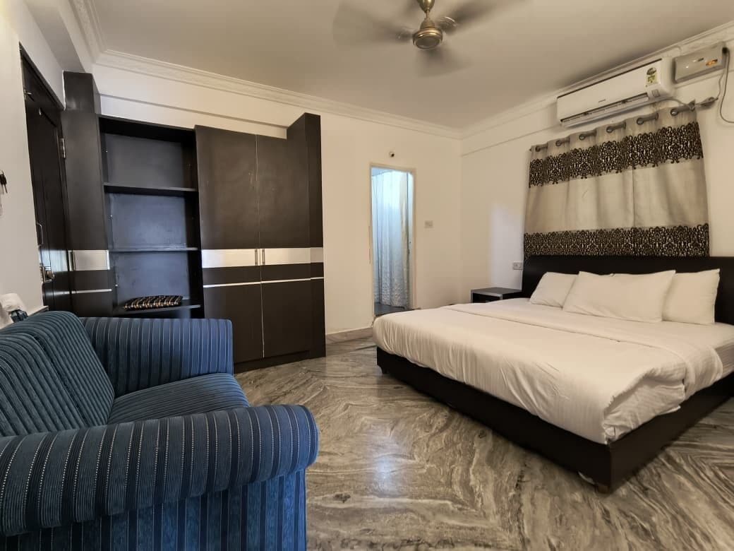 A bedroom with a bed, a sofa, a wardrobe, and a ceiling fan.