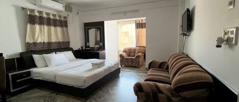 Habitación de hotel con cama, sofá, televisor y aire acondicionado.