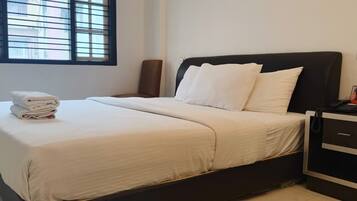 Una camera d'albergo con un letto, un comodino, una sedia e una finestra con persiane.