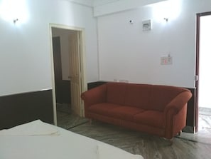 A room with a red sofa, a white table, and a door leading to another room.