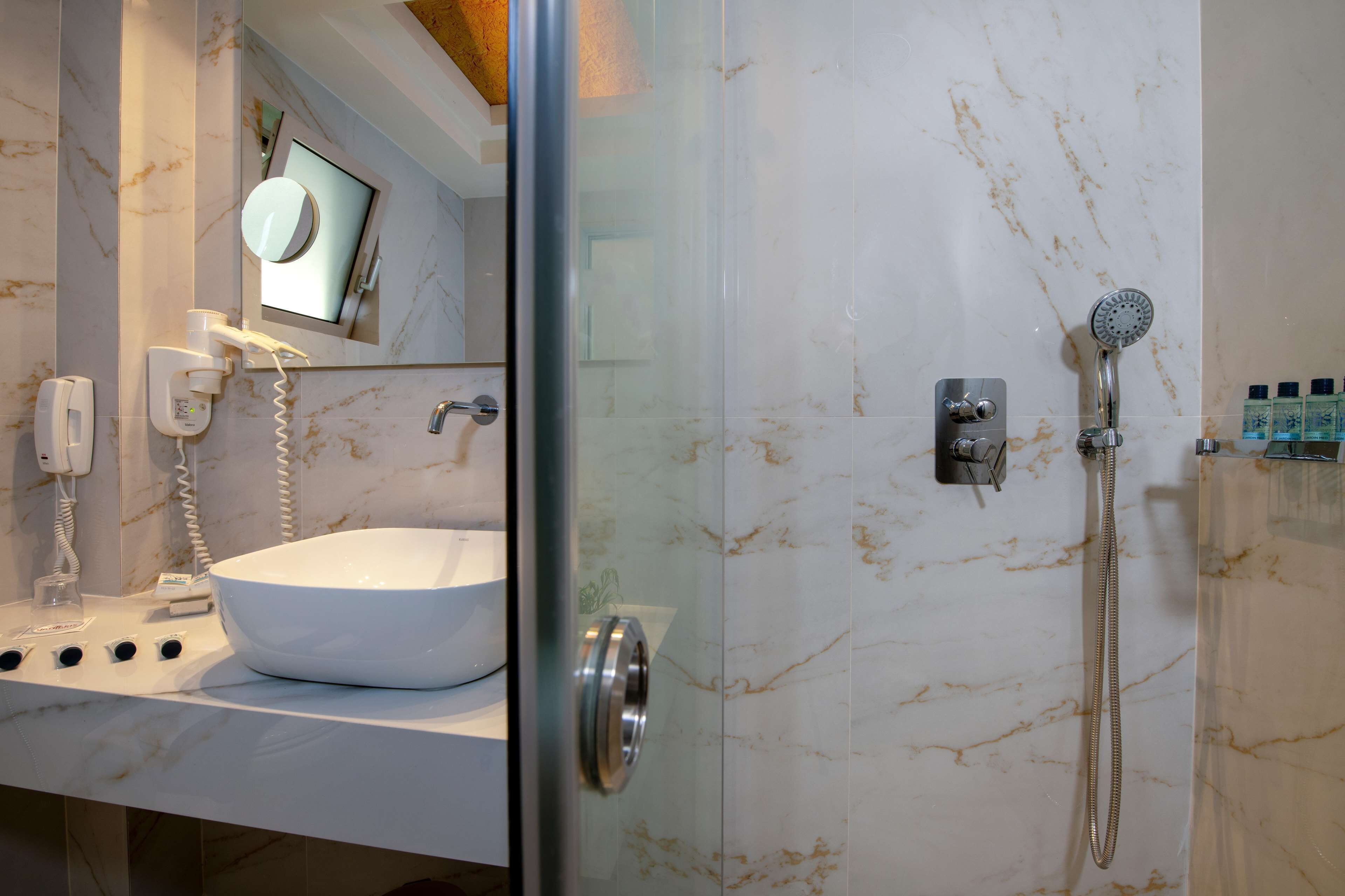 A modern bathroom with a glass-enclosed shower, a white sink, and a mirror above the sink.