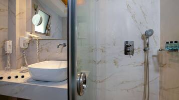 Un baño moderno con ducha acristalada, un lavabo blanco y un espejo sobre el lavabo.