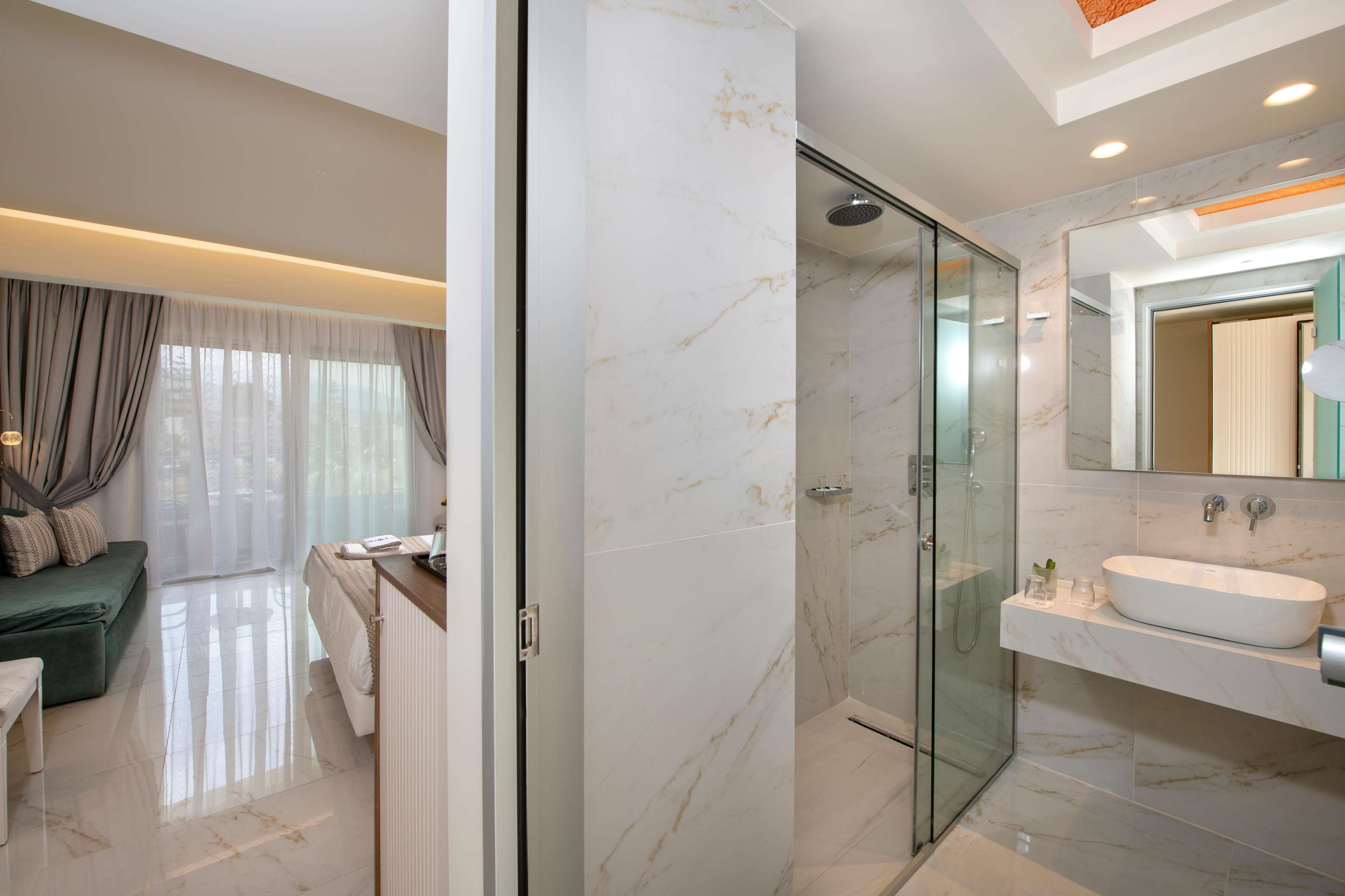 Un baño moderno con cabina de ducha de vidrio, un lavabo blanco y un espejo grande.
