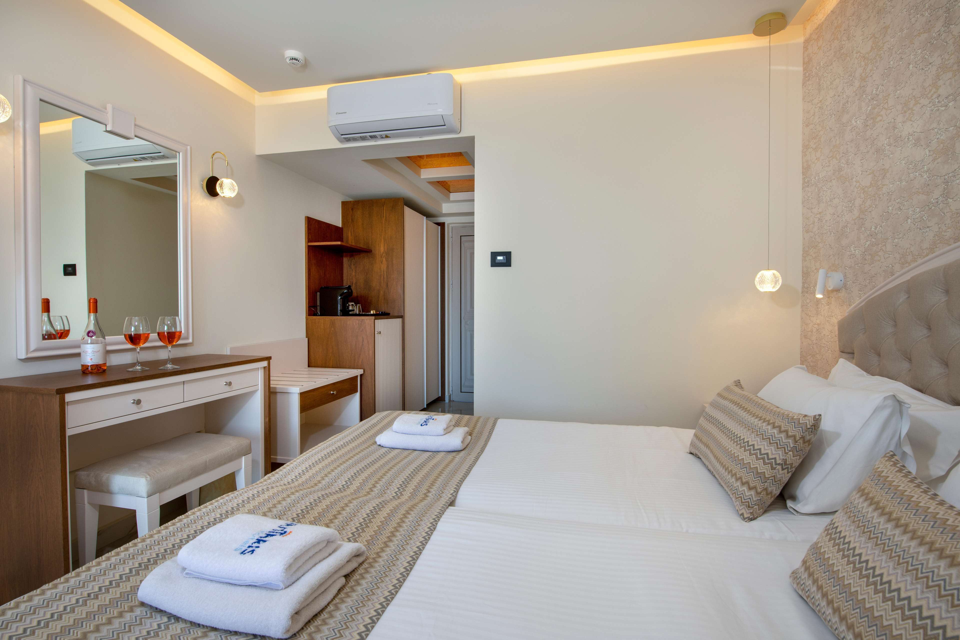 Quarto de hotel com cama, escrivaninha, cadeira, espelho e ar condicionado.