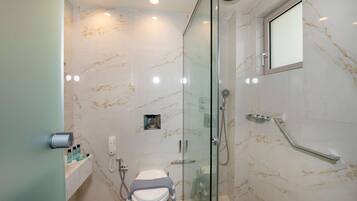 Un baño moderno con ducha de vidrio, inodoro y pared de mármol.