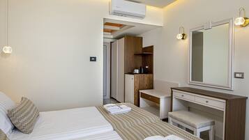 A hotel room with a bed, a desk, a chair, a mirror, and an air conditioning unit.