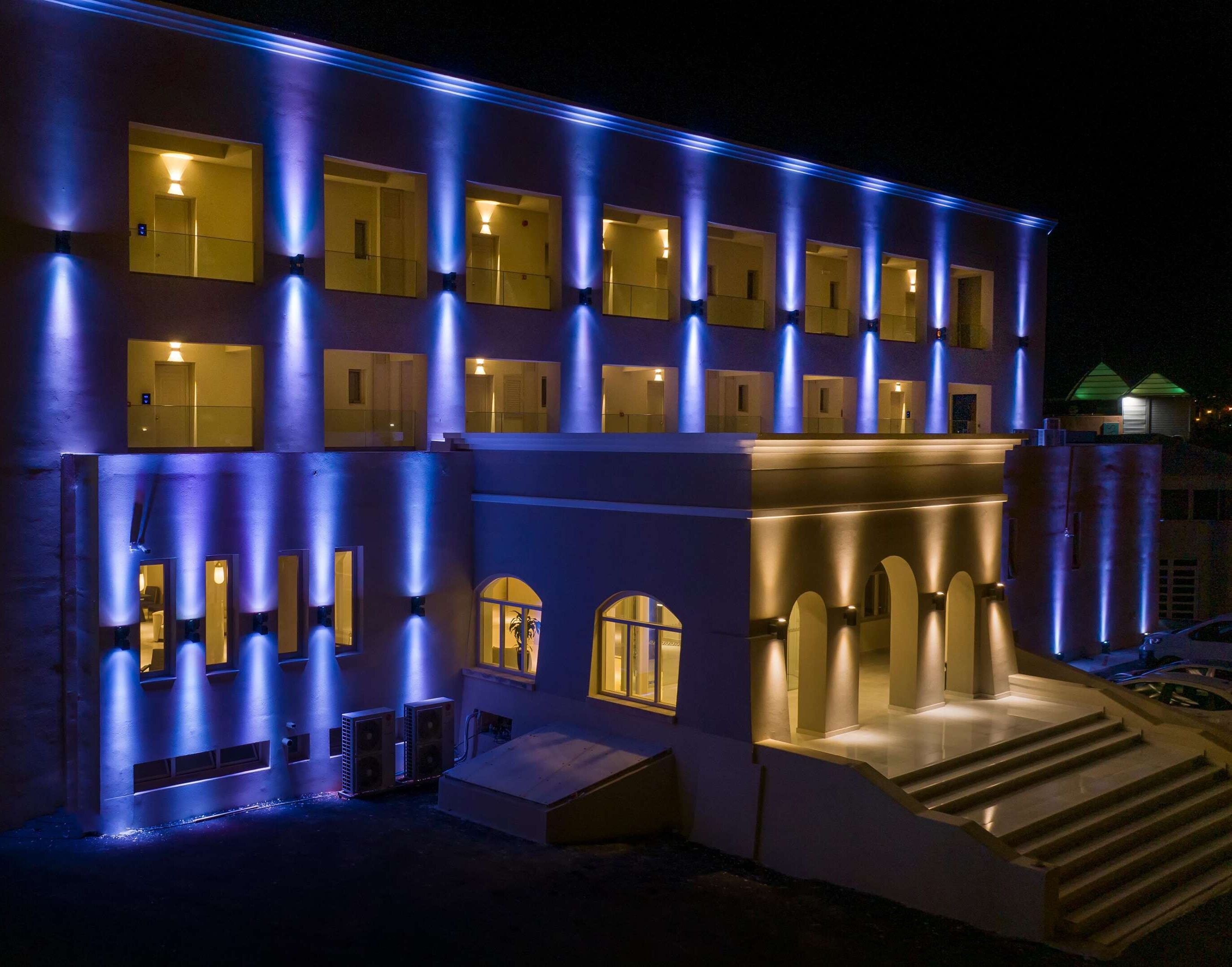 A hotel with multiple balconies, a central entrance with steps, and a series of windows.