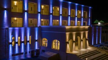 A hotel with multiple balconies, a central entrance with steps, and a series of windows.