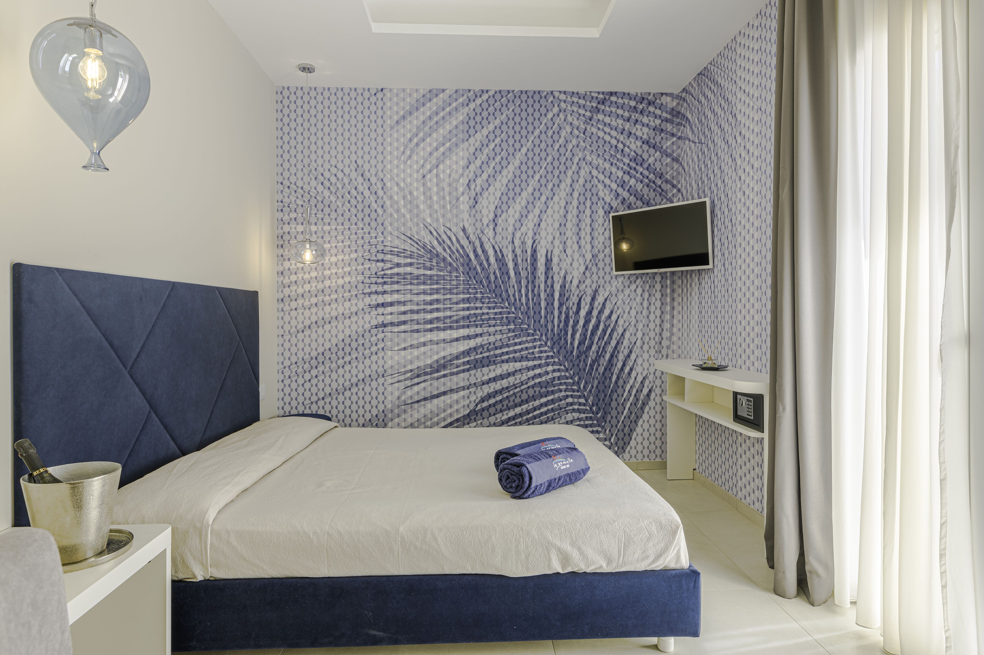A bedroom with a bed, a TV mounted on the wall, a bedside table, and a nightstand.