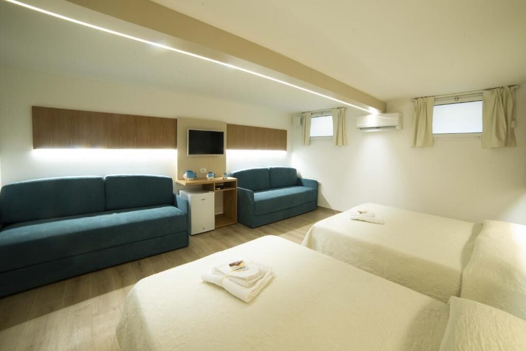 Une chambre d’hôtel avec deux lits, un canapé, un bureau et une télévision.