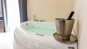 Een whirlpool met een ingebouwde verwarming, een handdouche en een flesje badzout.