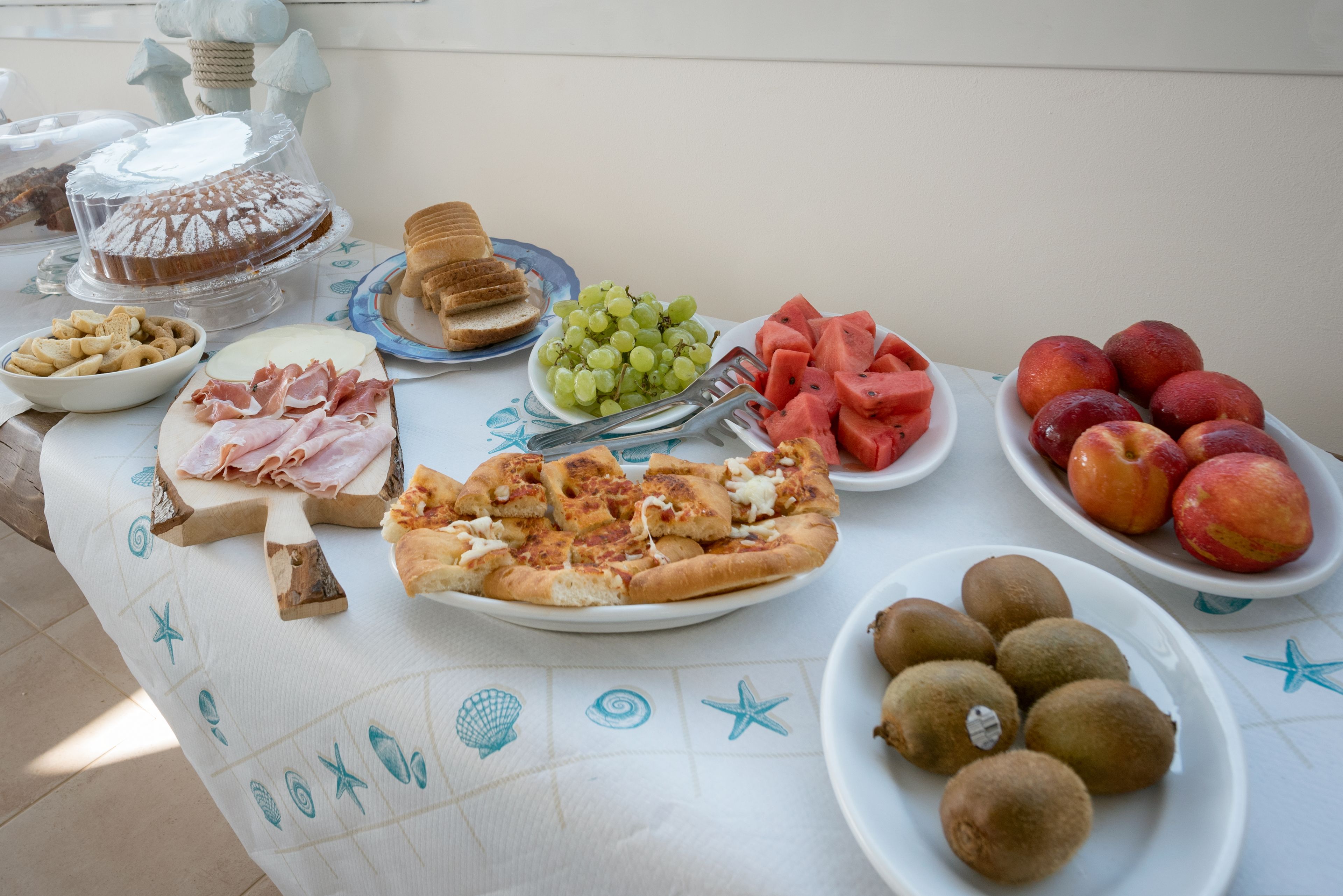 Uma mesa com diversos alimentos, incluindo pizza, frutas e bolo.