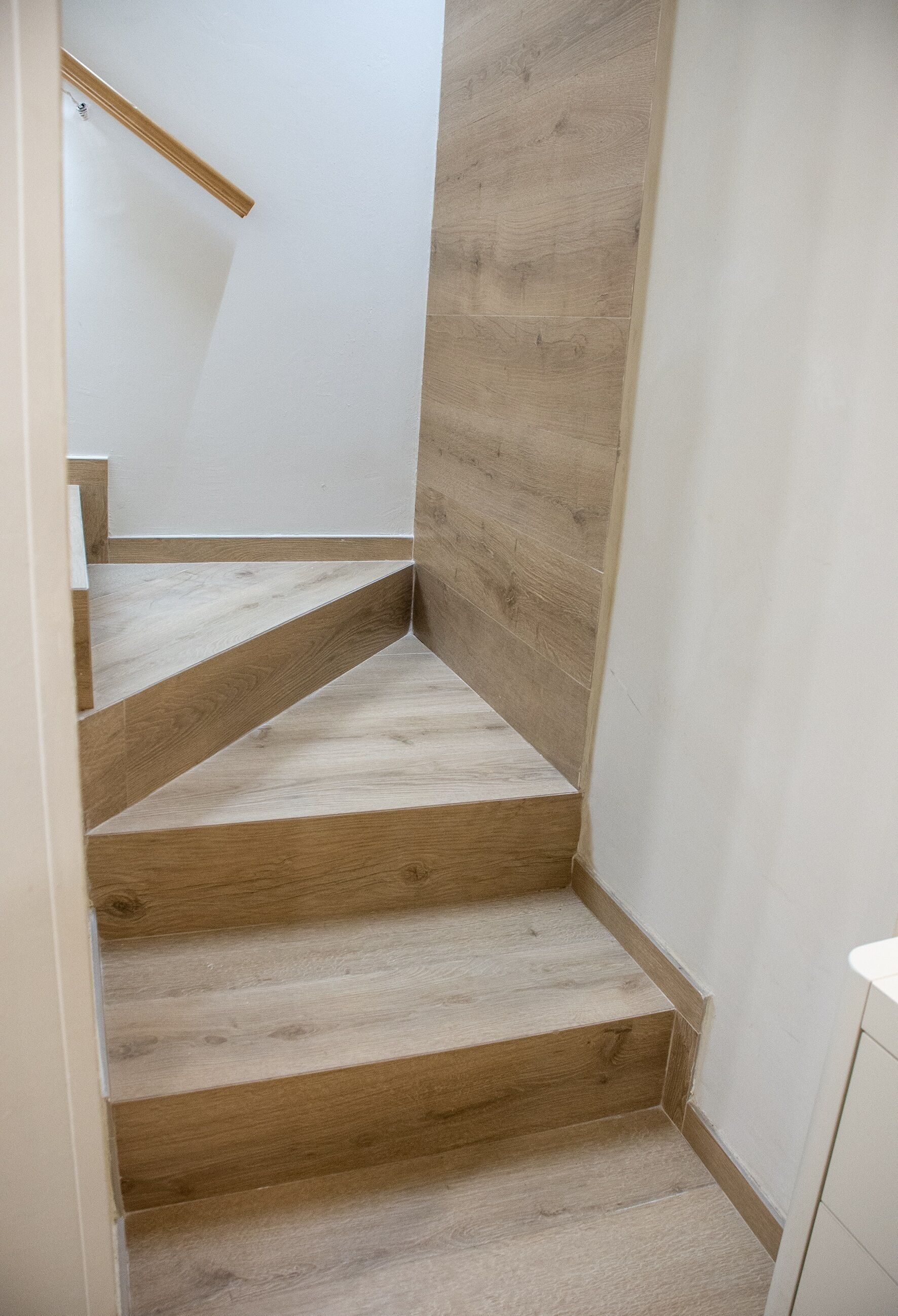 Una escalera de madera con barandilla que lleva a una plataforma.