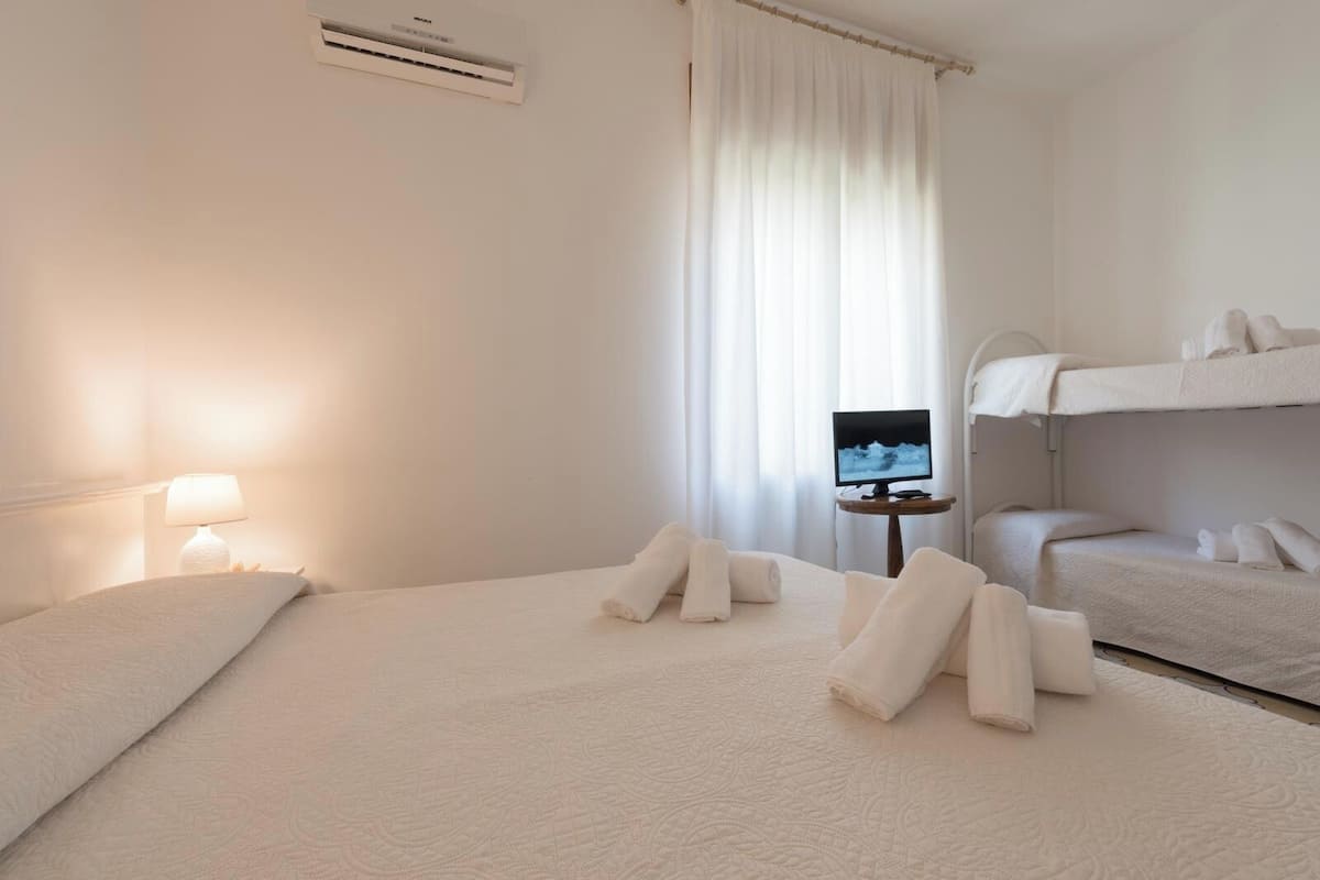 Una habitación de hotel con una cama, un televisor, una mesita de noche y una litera.