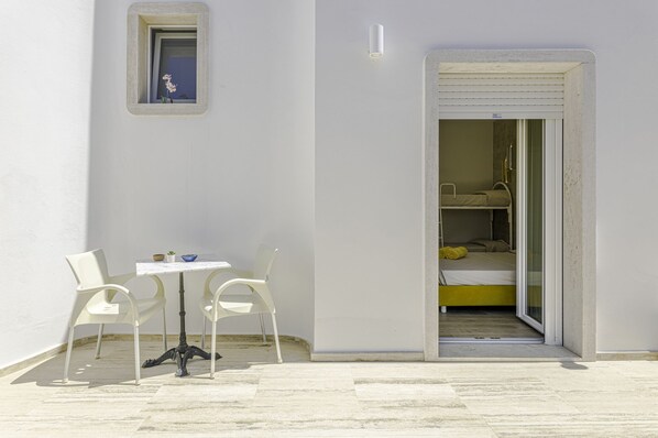 Una habitación pequeña y privada con cama, una silla y una mesa.