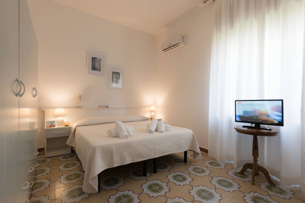 Habitación de hotel con una cama, dos lámparas de noche, un televisor y un suelo con diseño.