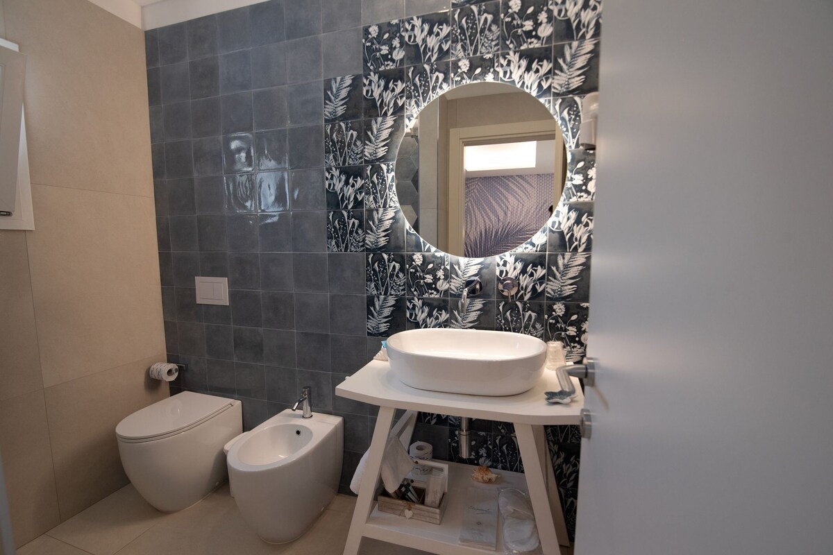 Un baño con inodoro, bidé y lavamanos con espejo.