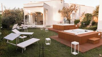 Un espace de détente extérieur moderne, doté de chaises longues, d’un jacuzzi et d’une terrasse en bois.