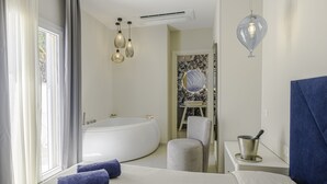 Een moderne badkamer met een vrijstaand bad, een wastafel met een decoratieve spiegel, en een hanglamp.