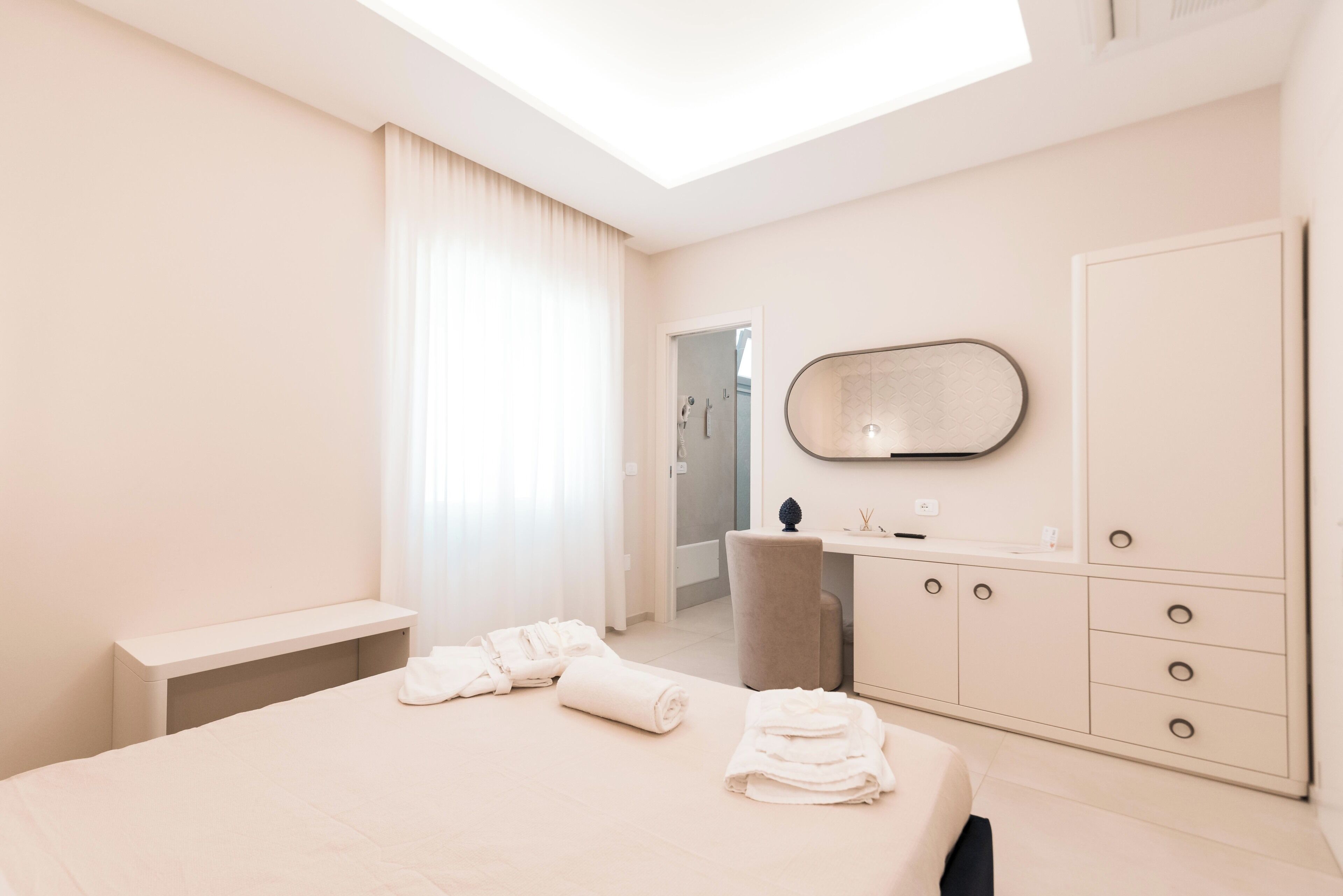 Una habitación de hotel moderna con una cama, un escritorio, una silla, un espejo y la puerta del baño.