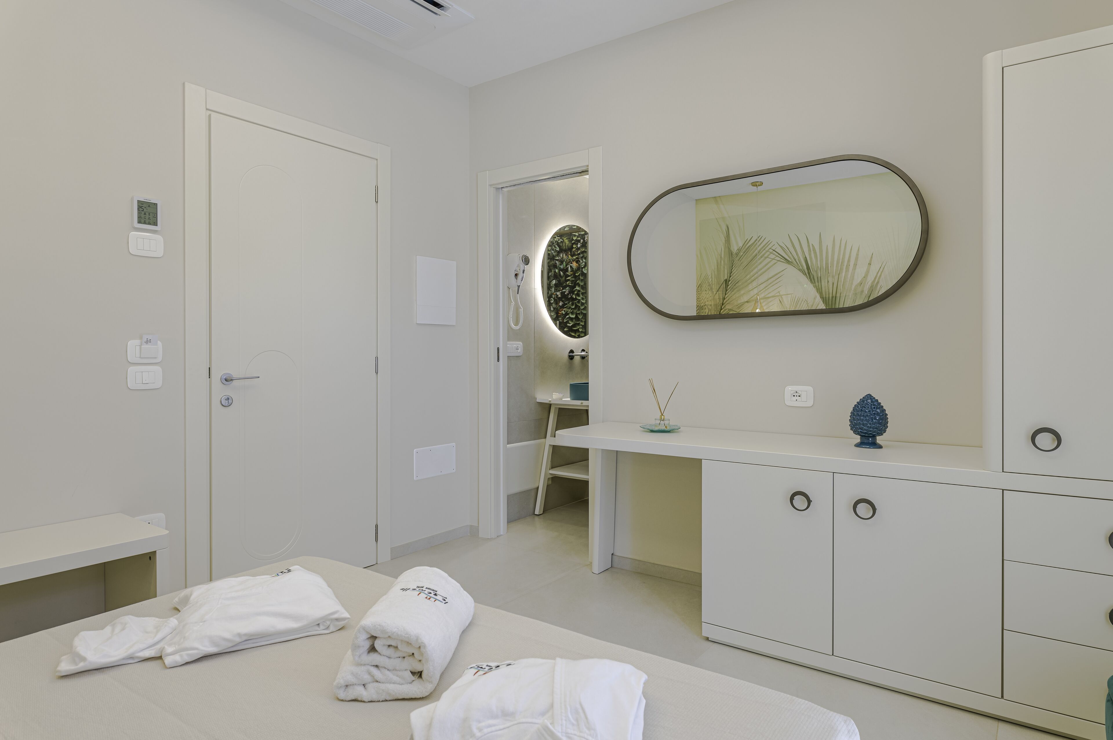 A modern bathroom with a white vanity, a large mirror, and a shower area.