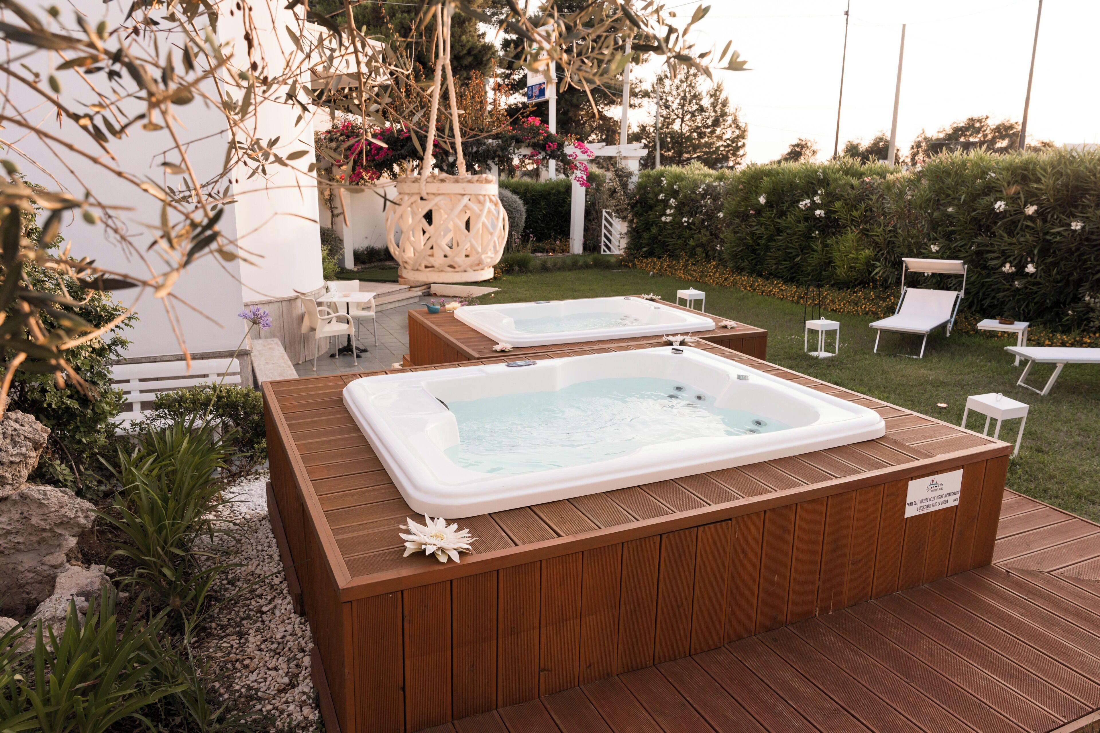 Twee jacuzzi's op een houten terras, met een tuin op de achtergrond.