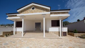 Una casa moderna con ingresso in pietra, un portico coperto e una porta centrale.