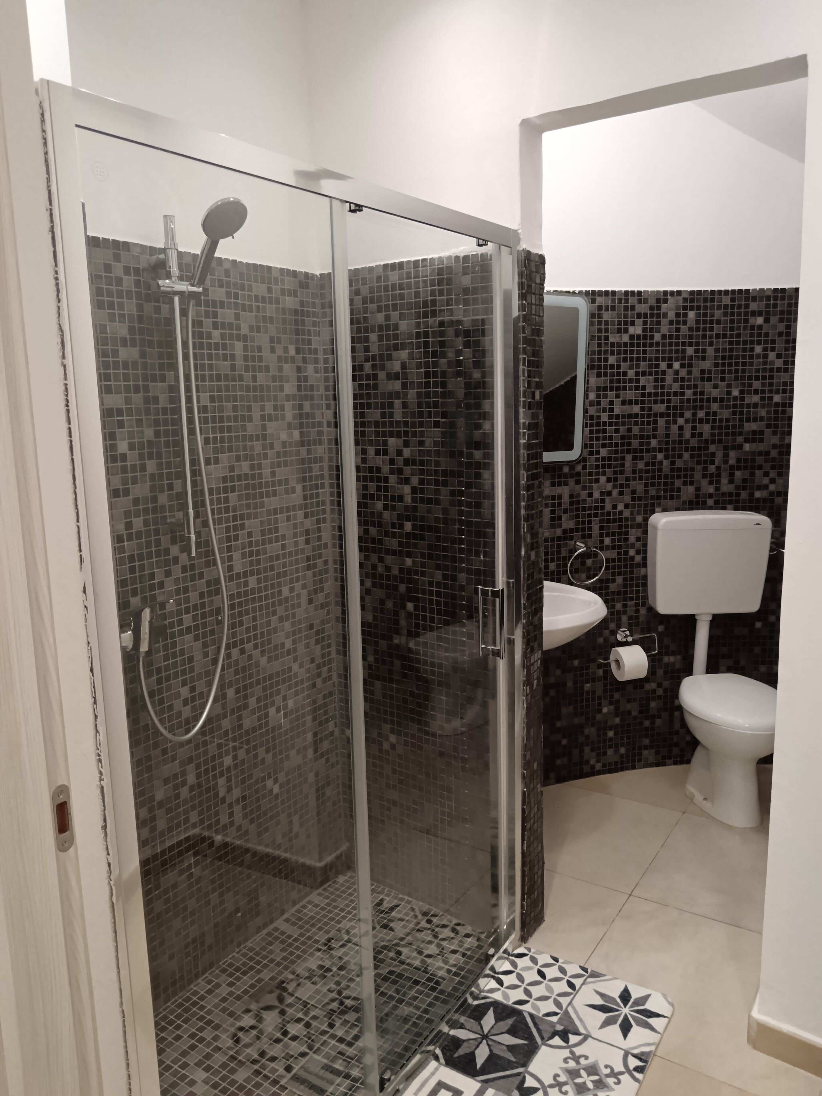 A bathroom with a glass-enclosed shower, a white toilet, and a sink.