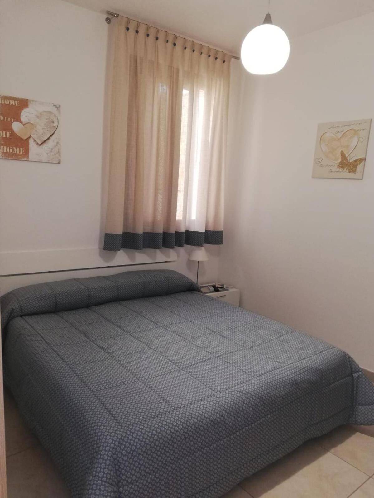 A bedroom with a bed, curtains, a wall clock, and a light fixture.