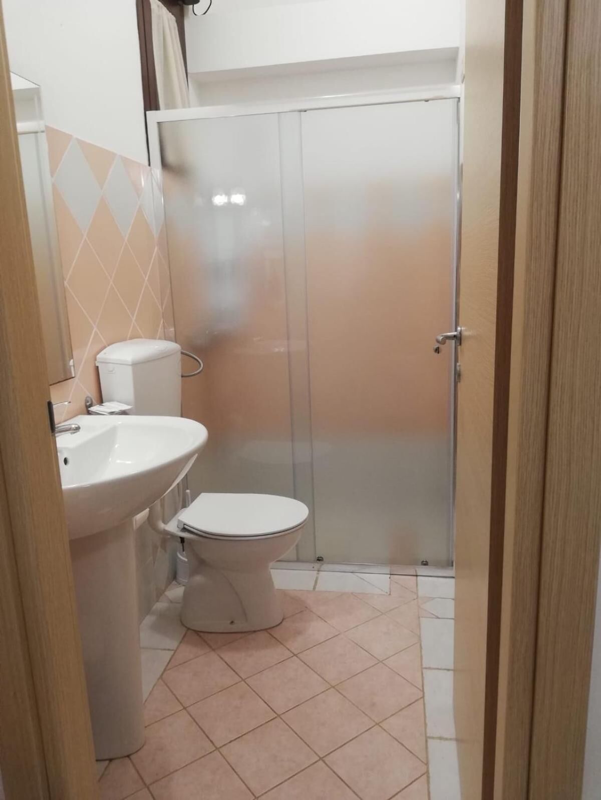 A small bathroom with a sink, toilet, and a shower stall.