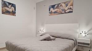 Camera da letto moderna con un letto grande, una testiera bianca e due comodini con lampade.