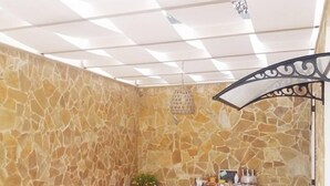 Una stanza con pareti in pietra, arredi bianchi e un soffitto decorato.