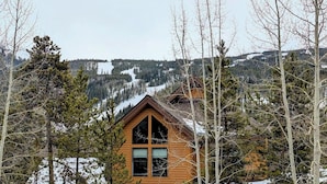A cabin with a gabled roof, surrounded by trees and a snowy landscape. - Gateway Lodge 5030 by SummitCove Vacation Lodging (Keystone)
