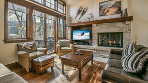 A spacious living room with large windows, a fireplace, and a television. - Keystone Sanctuary 248 by SummitCove Vacation Lodging (Keystone)