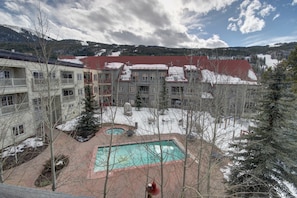 A hotel with multiple buildings, a swimming pool, and a snowy landscape with mountains in the background. - Expedition Station 8607 by SummitCove Vacation Lodging (Keystone)