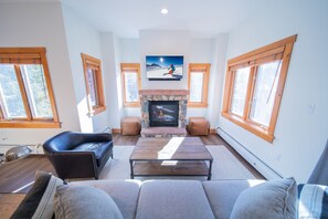 A living room with a fireplace, a sofa, and a television mounted above it.