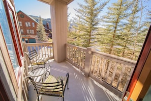 A balcony with a wooden railing, a table, and two chairs.