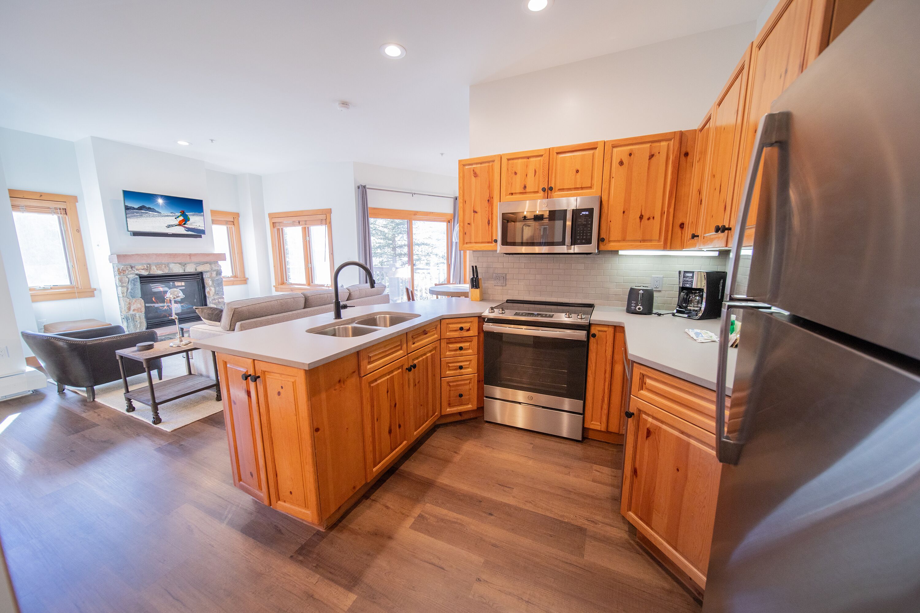 A modern kitchen with wooden cabinets, stainless steel appliances, and a stone fireplace.
