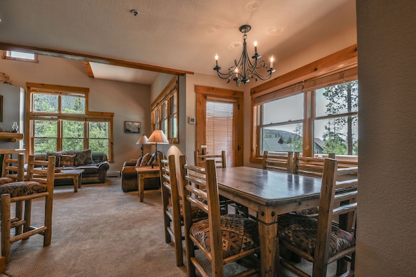 A spacious dining area with wooden furniture, large windows, and a chandelier. - Trappers Crossing 8753 (Keystone)