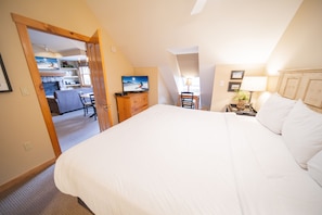 A bedroom with a large bed, a desk, a chair, a television, and a lamp. - Buffalo Lodge 8411 by SummitCove Vacation Lodging (Keystone)