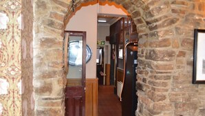 A stone archway leading into a room with a wooden door and a circular mirror on the wall. - Oak Tree Inn (Stanley)
