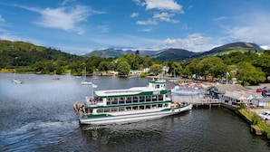 A ferry docked at a harbor with a mountainous backdrop.