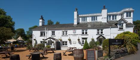 A white building with a sign reading "The Wateredge Inn" and a signboard indicating it serves food, beer, and has a garden.