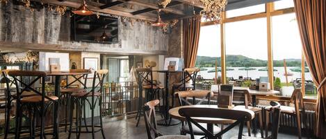 A restaurant with wooden furniture, large windows, and a view of the outdoors.