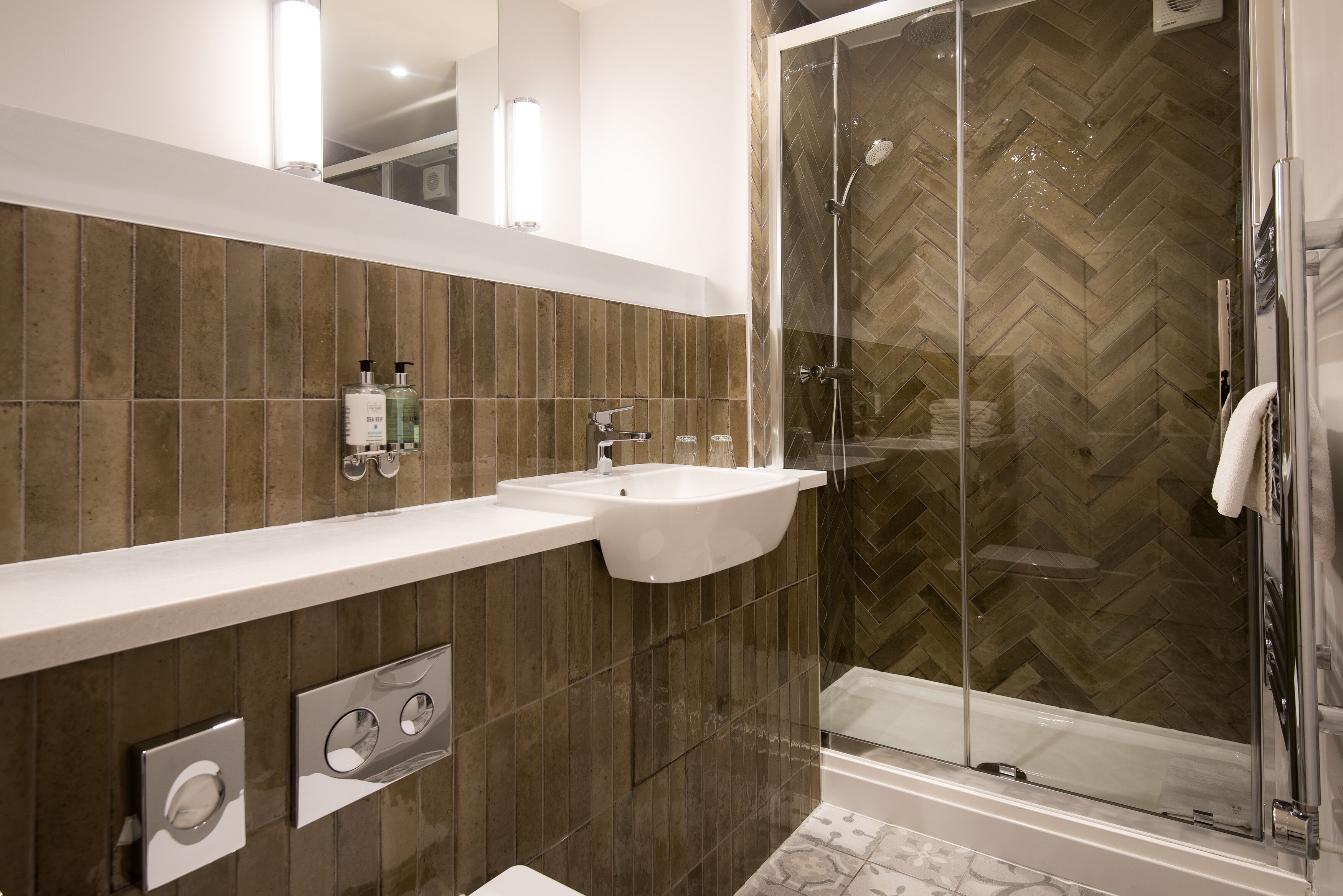 A modern bathroom with a large mirror, a sink, and a glass-enclosed shower.